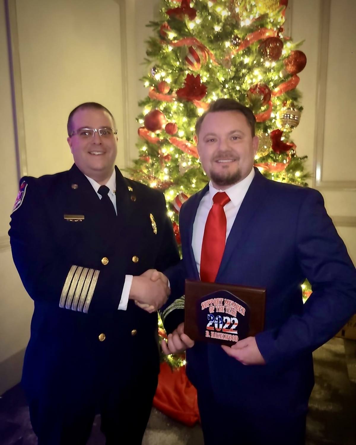 Derek Hazelwood accepting a South Hill Volunteer Fire Department award from a chief officer in dress uniform