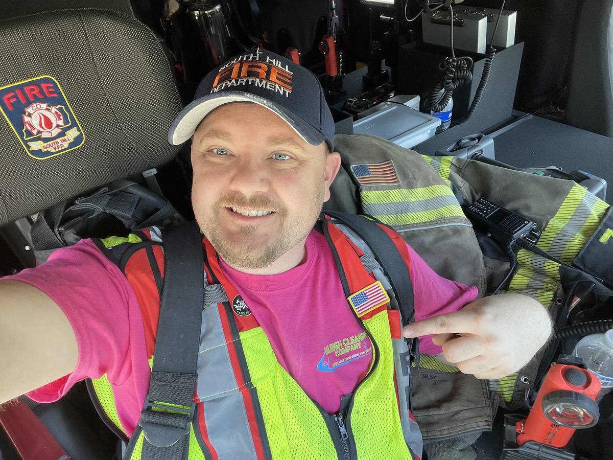 Derek Hazelwood in the apparatus cab in traffic vest and air pack straps
