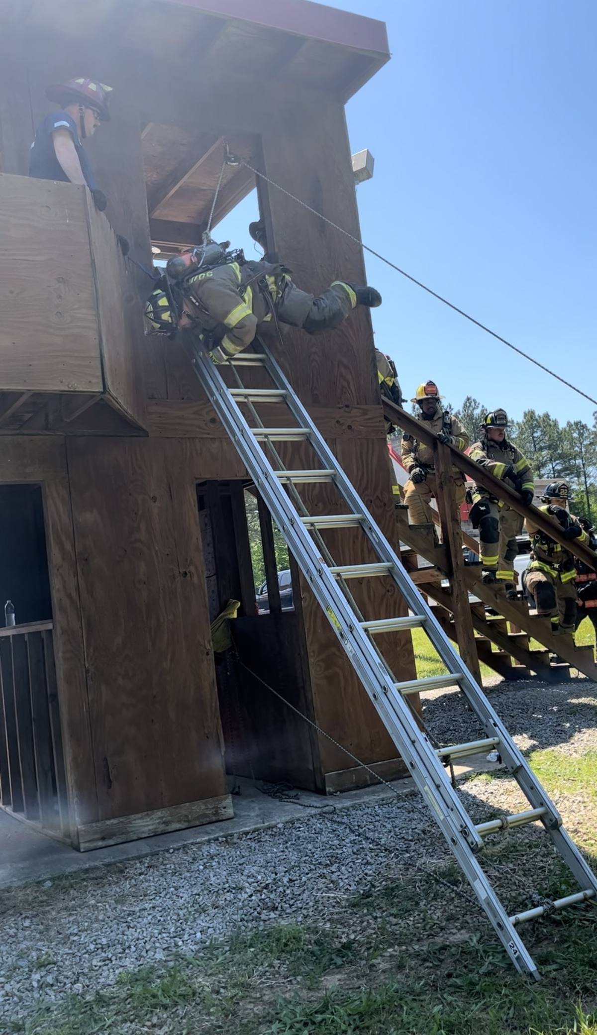 Firefighter climbing to the training tower window on a ground ladder