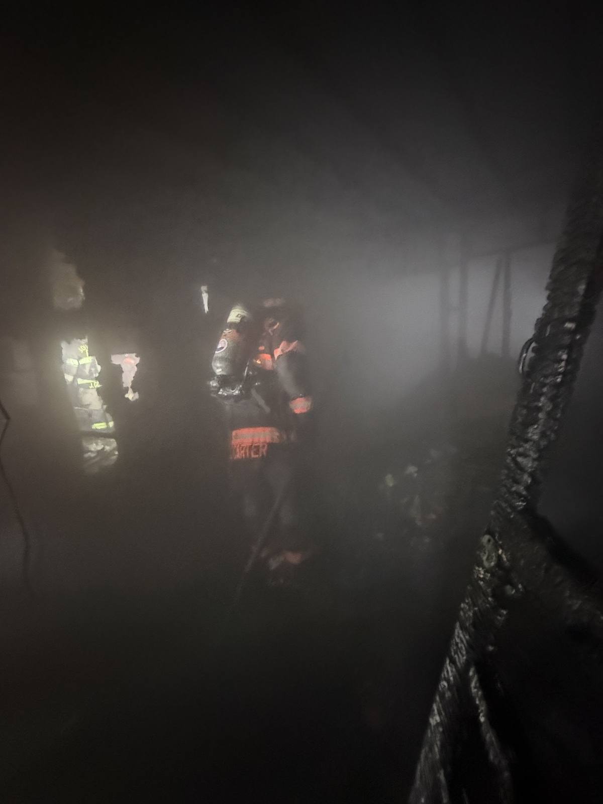 Firefighter advancing through heavy smoke inside a burning structure