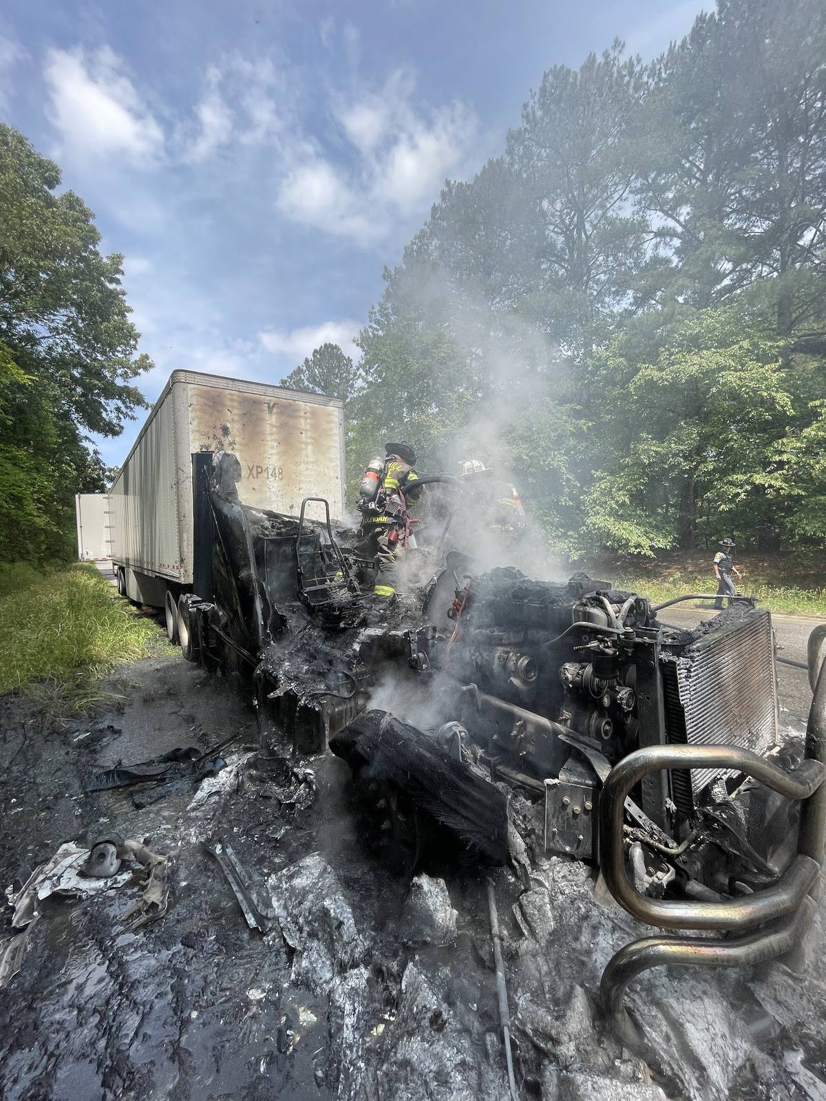 Burned out tractor trailer cab still smoking after a highway fire