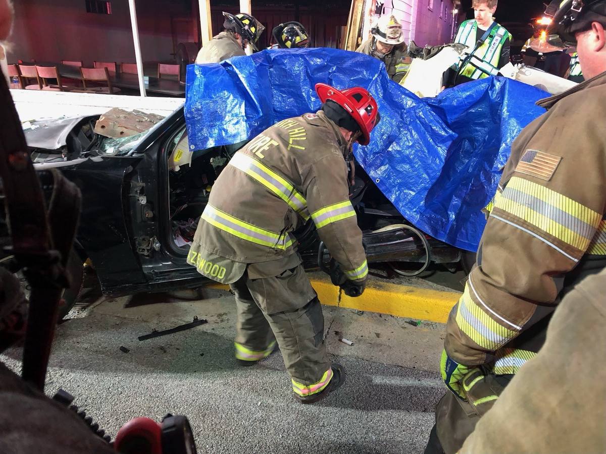 Firefighter cutting a vehicle post during an extrication