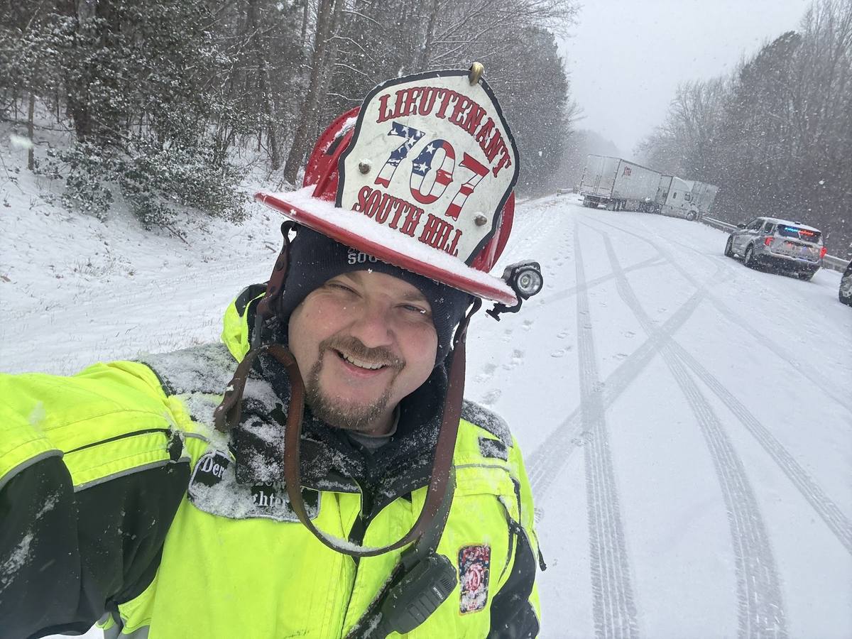 Lieutenant Derek Hazelwood working a snow covered highway with a jackknifed truck behind him
