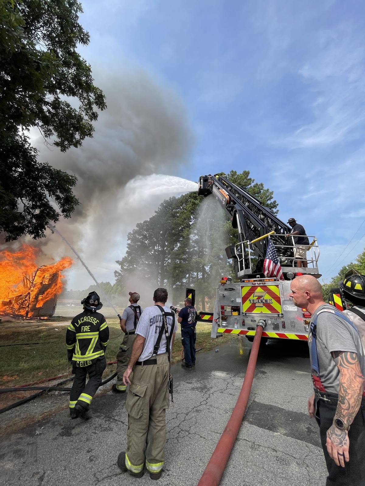 Aerial ladder flowing water at a working fire while the crew watches from the street