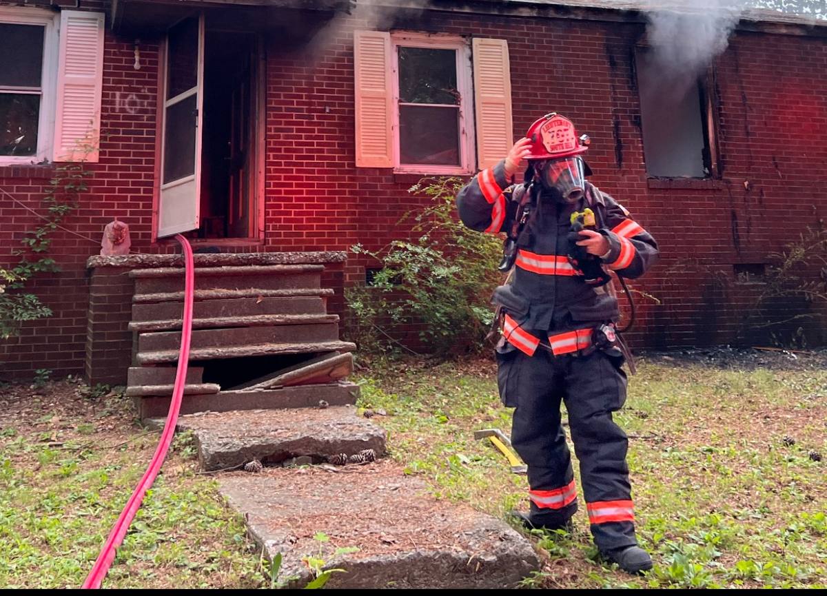Firefighter on air outside a smoking brick house, South Hill Virginia